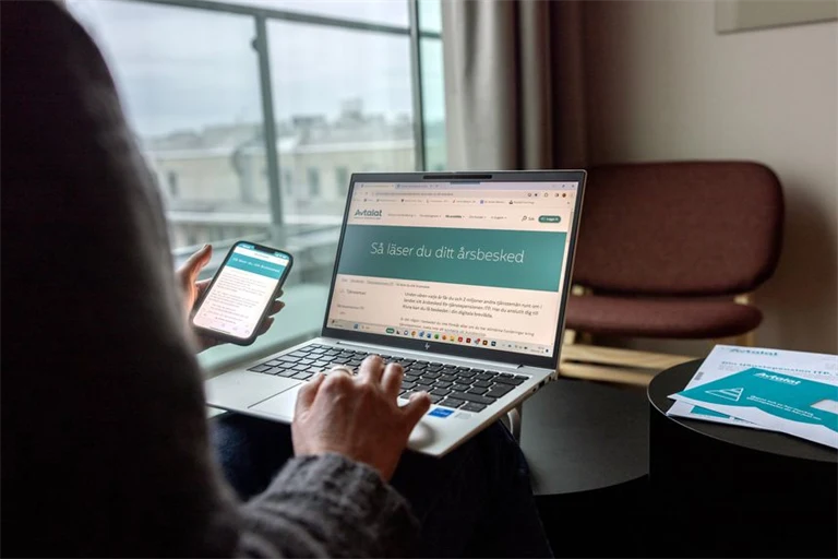 Skrivbord med mobil och laptop som visar Avtalats webbplats.
