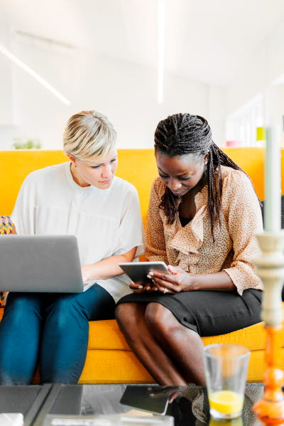 Två kvinnor i soffa tittar i en ipad