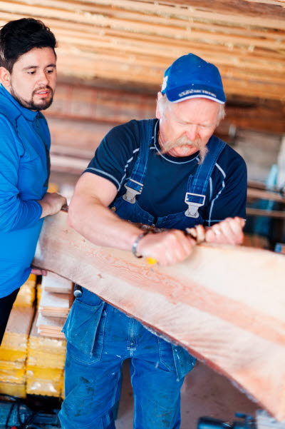 Två snickare karvar på en planka