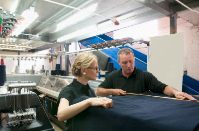 Man och kvinna mäter tyg i textilfabrik