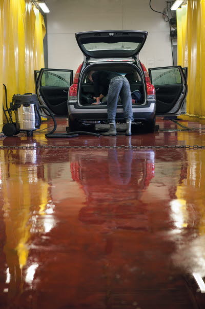 Biltvättare i tvätthall städar inuti en bil