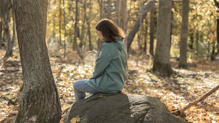 Kvinna sitter på sten i skogen