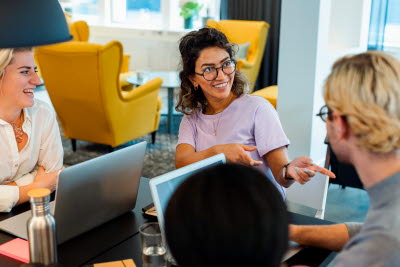 Glada kollegor samtalar vid sina datorer