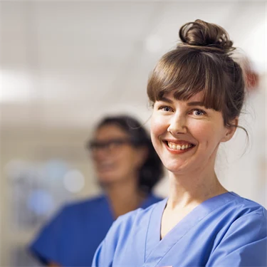 en undersköterska på en vårdcentral som ser glad ut och samtalar med kollegor i korridoren