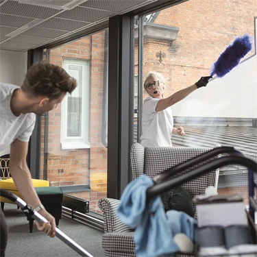 En manlig och kvinnlig städare städar på ett kontor.