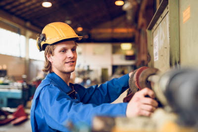Man med gul hjälm arbetar i fabrik