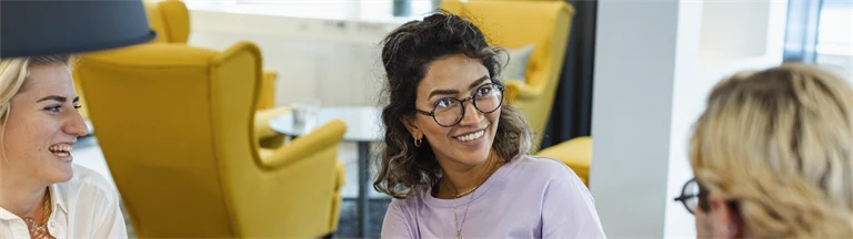 Glada kollegor samtalar vid bord med datorer.