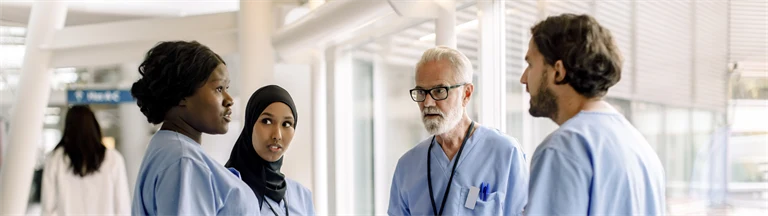 En grupp med vårdpersonal står och samtalar i korridor