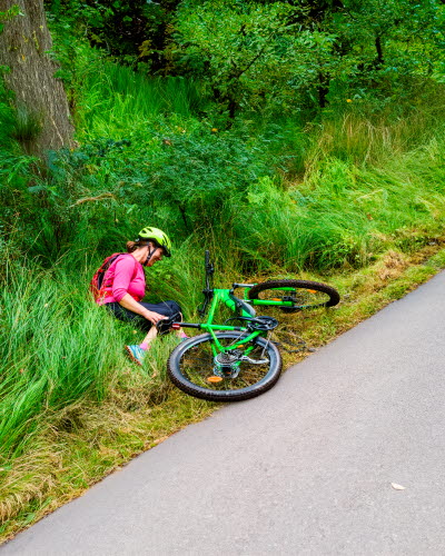 Kvinna sitter i diket med sin cykel