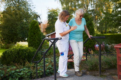 Kvinna på promenad med vårdpersonal.