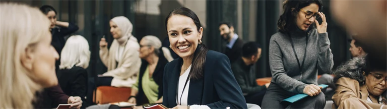 Leende affärskvinna diskuterar med kollegor på konferens