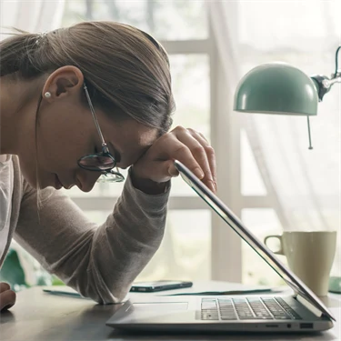 Ung kvinnar lutar sig mot dator