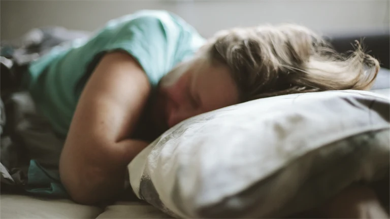 Kvinna som sover med huvudet på en kudde