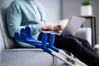 Kryckor på soffan, framför en kvinna med laptop