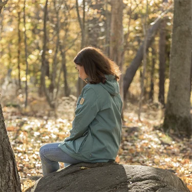 Kvinna sitter på sten i skogen