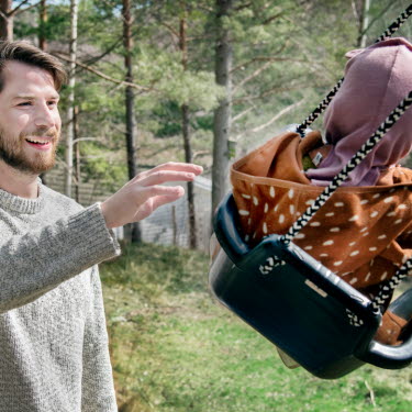 Man gungar barn utomhus i fint väder.