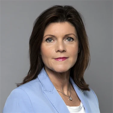 Arbetsmarknadsminister Eva Nordmark i ljusblå kavaj mot grå bakgrund.