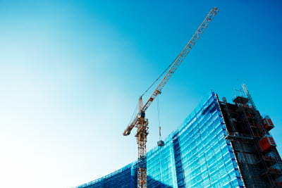 Lyftkran framför ett höghus med glasfasad