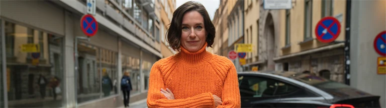 Person som står ute vid en gata. Bakom hen är en bil parkerad.