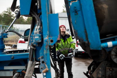 Kvinna i arbetskläder manövrerar en stor maskin