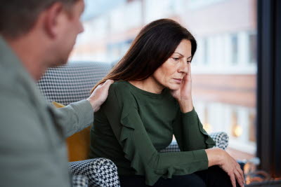 Kvinna får tröst med hand på axeln.