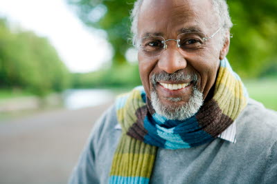 Man med grått skägg och halsduk i en park