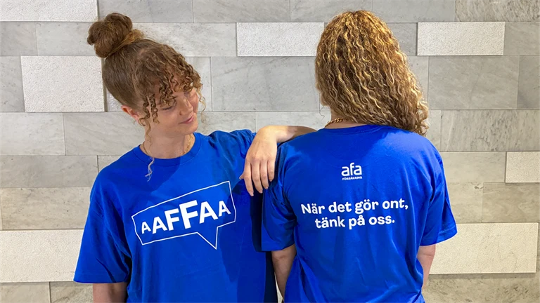 Två Afa-medarbetare i t-shirts med texten: När det gör ont, tänk på oss.