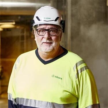 Jörgen Rydberg står på fabriksgolvet. Han har skyddshjälm och varselkläder på sig.