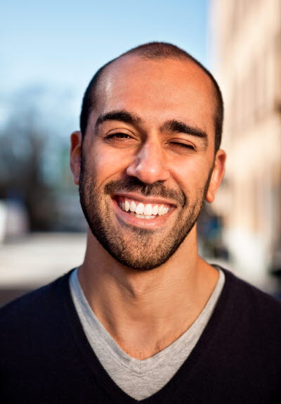 Man med skäggstubb och svart tröja en solig dag