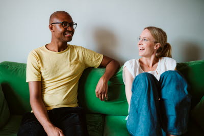 Man och kvinna skrattar i grön soffa