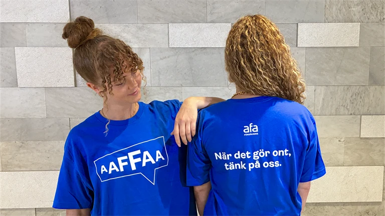 Två Afa-medarbetare i t-shirts med texten: När det gör ont, tänk på oss.