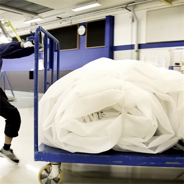 Duang-Jan Larsson arbetar i lagsalen på Voith, med att manuellt dra en vagn med vävar som man manuellt flyttar till nästa avdelning.