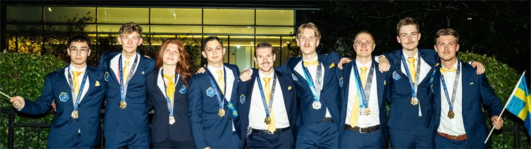 Tävlande i svenska yrkeslandslaget poserar för gruppbild i finkläder och med medaljer i band runt halsen.