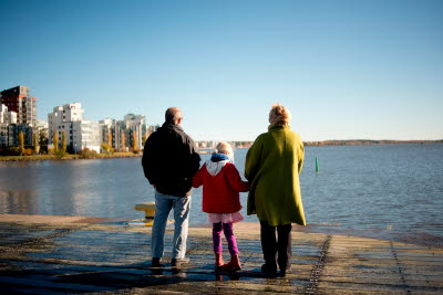 Man, flicka och kvinna ser ut över hav och höghus