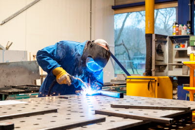 Svetsare med svetshjälm arbetar i en verkstad