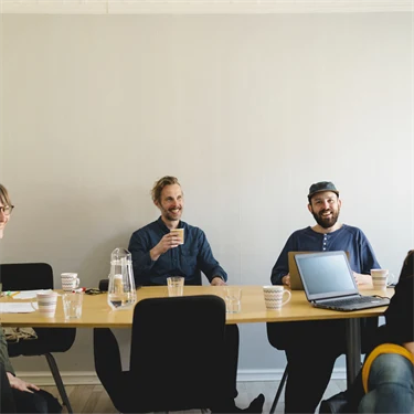En grupp av glada människor runt ett konferensbord