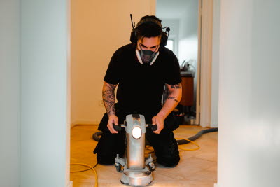 Arbetare i munskydd slipar golv