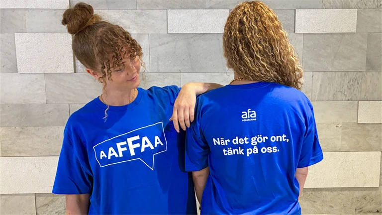 Två Afa-medarbetare i t-shirts med texten: När det gör ont, tänk på oss. 