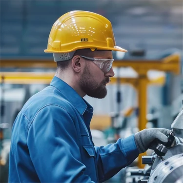 Man med hjälm arbetar med en maskin på fabrik