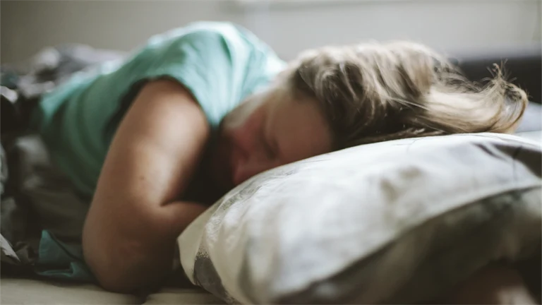 Kvinna som sover med huvudet på en kudde