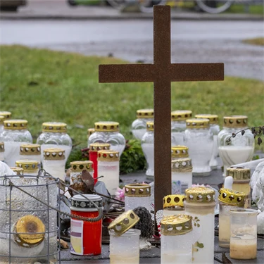 Gravlyktor och ett kors på gräsmattan framför Campus Risbergska.