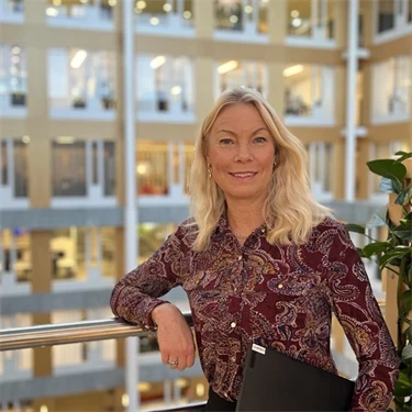 Martina Rex från Afa Försäkring står vid ett räcke med sin laptop i handen.