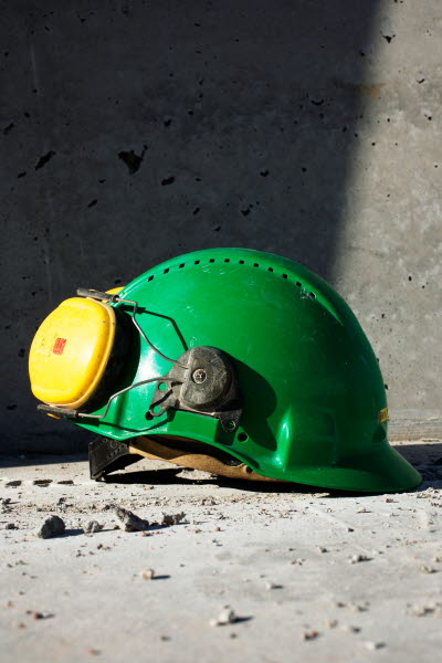 Grön bygghjälm med gula hörselkåpor