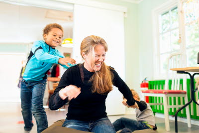 Barn busar med kvinna som sitter på golvet