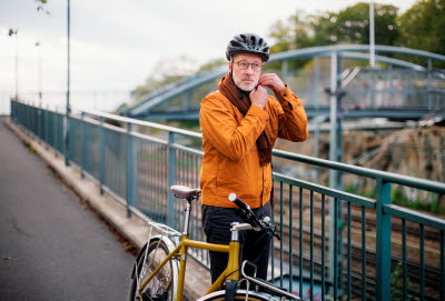 Man med cykel knäpper cykelhjälmen