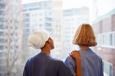 Vårdbiträden blickar ut genom fönster.