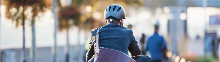 Man i kavaj cyklar med datorväska hängandes över ryggen