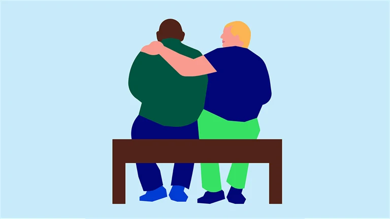 två personer sitter på en bänk och håller om varandra