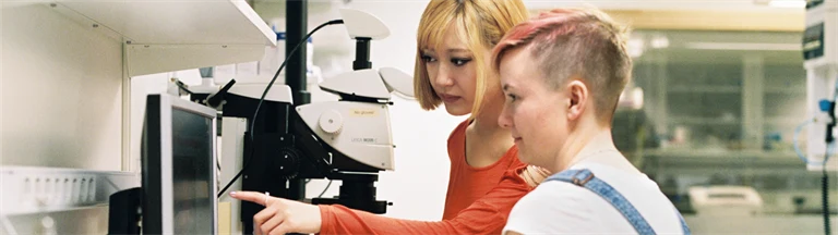 Två unga personer i ett laboratorium jobbar vid en dator.