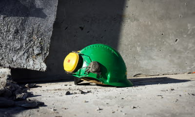 Bygghjälm med hörselkåpor på ett betonggolv